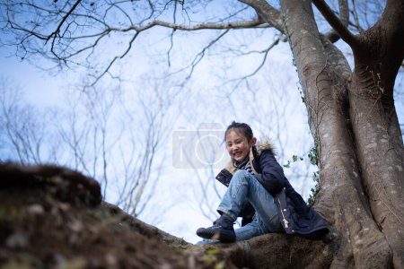 Photo for Girl sitting on a tree trunk - Royalty Free Image