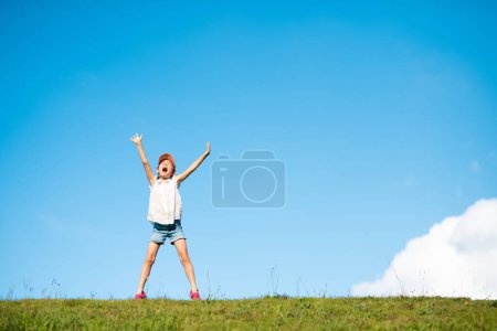 Photo for Child shouting with both hands raised in the meadow - Royalty Free Image