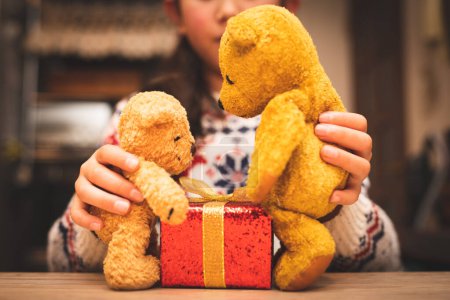 Téléchargez les photos : Un enfant jouant avec un ours en peluche et une boîte cadeau - en image libre de droit