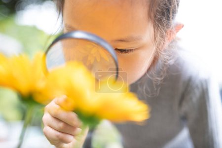 Téléchargez les photos : Fille regardant des fleurs avec une loupe - en image libre de droit