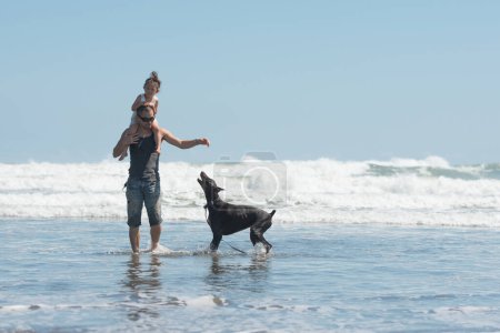 Téléchargez les photos : Père et fille et chien jouant sur la plage - en image libre de droit