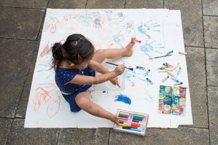 Téléchargez les photos : Fille peinture sur papier à l'extérieur - en image libre de droit