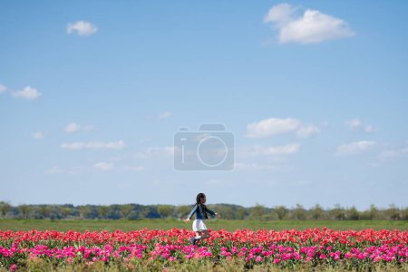 Photo for Cute asian little girl   on field of tulips - Royalty Free Image