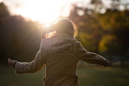 Téléchargez les photos : Fille jouer dans le parc au coucher du soleil - en image libre de droit