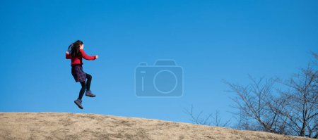 Foto de Chica saltando bajo el cielo azul - Imagen libre de derechos