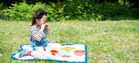 Foto de Un niño almorzando en el césped - Imagen libre de derechos