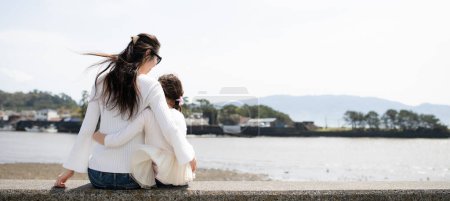 Téléchargez les photos : Mère et fille assis et regardant la mer - en image libre de droit