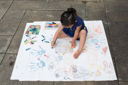 Photo for Girl painting on paper outdoors - Royalty Free Image