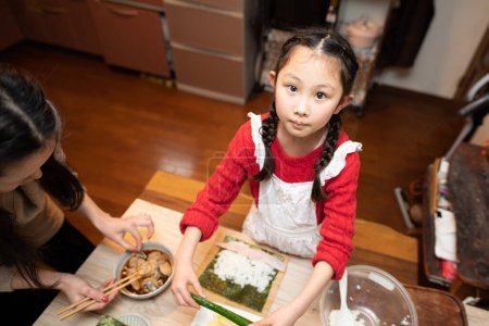 Photo for Mother and daughter making sushi rolls - Royalty Free Image