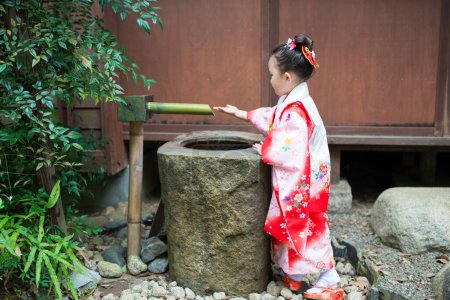 Chica jugar usando un kimono en el jardín japonés