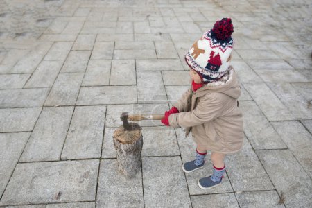 Foto de Niño en ropa de invierno con hacha en el parque - Imagen libre de derechos