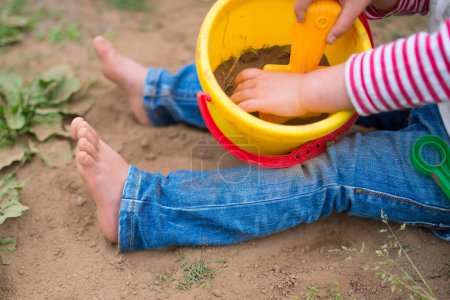 Photo for Child playing barefoot with basket - Royalty Free Image