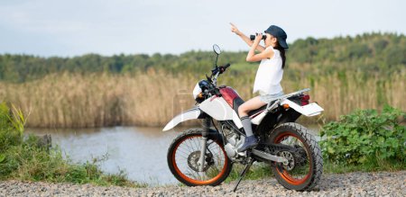 Photo for Girl riding an off-road bike and looking into the distance with binoculars - Royalty Free Image