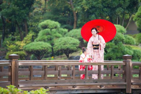 Téléchargez les photos : Asiatique fille et femme portant robe traditionnelle dans le jardin - en image libre de droit