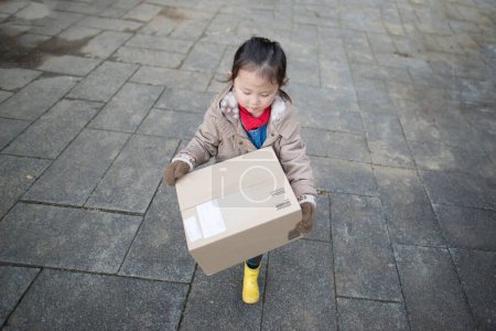 Téléchargez les photos : Fille avec boîte en carton marche dans la ville - en image libre de droit