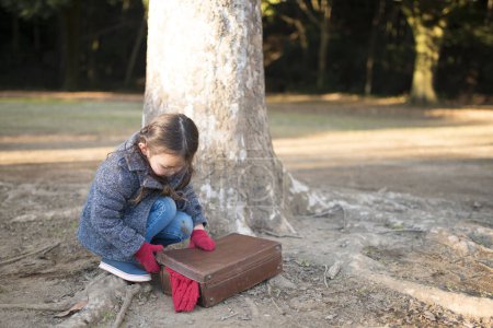 Téléchargez les photos : Petite fille emballant des bagages dans la forêt - en image libre de droit