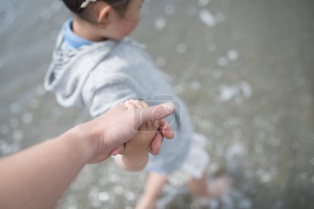 Téléchargez les photos : Parent et enfant se tenant la main à la plage - en image libre de droit