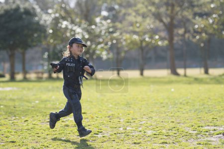Téléchargez les photos : Bonne petite fille courir en costume de police - en image libre de droit