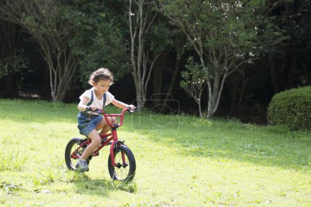 Téléchargez les photos : Petite fille en vélo rouge - en image libre de droit