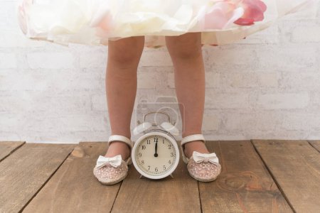 Photo for Girl legs and alarm clock wearing a dress - Royalty Free Image