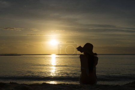 Téléchargez les photos : Silhouette de belle femme relaxante sur la plage du coucher du soleil - en image libre de droit
