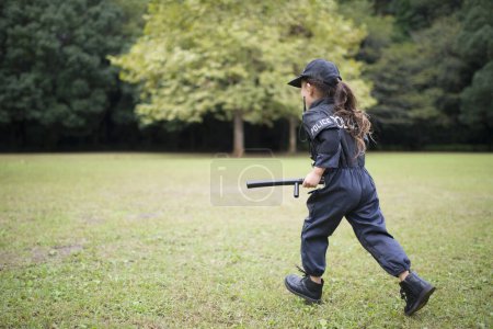 Photo for Girl wearing a police costume running on lawn - Royalty Free Image