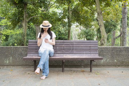 Photo for Woman to use the smartphone on bench - Royalty Free Image