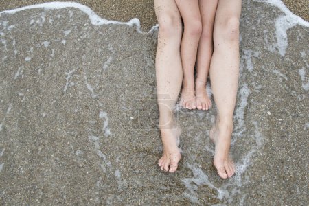 Téléchargez les photos : Pieds de la mère et de l'enfant pour s'asseoir sur la plage - en image libre de droit