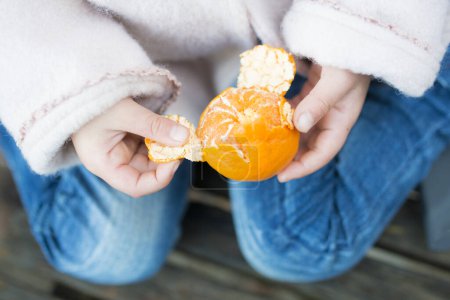 Téléchargez les photos : Peler une peau de mandarine - en image libre de droit