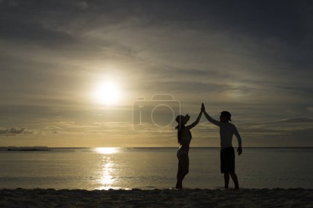Foto de Siluetas de hombre y mujer en la playa del atardecer - Imagen libre de derechos