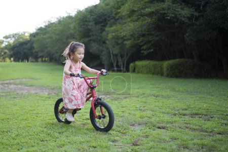 Photo for Little girl riding a red Bicycle - Royalty Free Image