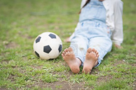 Descalza niña jugando con una pelota de fútbol