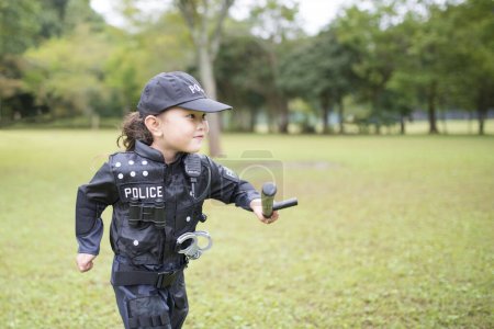 Téléchargez les photos : Fille portant un costume de police courir sur la pelouse - en image libre de droit