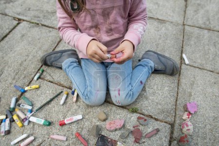 Téléchargez les photos : Fille peinture avec des couleurs sur le trottoir de pierre - en image libre de droit