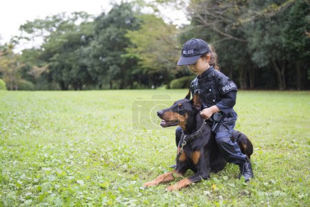Téléchargez les photos : Fille portant un costume de police faisant une patrouille avec un doberman - en image libre de droit