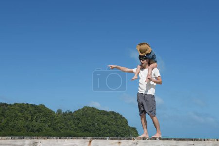 Téléchargez les photos : Père et fille marchant avec une roue d'épaule sur la plage - en image libre de droit