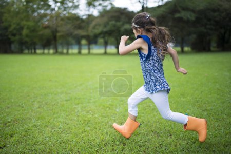 Téléchargez les photos : Petite fille à sprint sur la pelouse - en image libre de droit