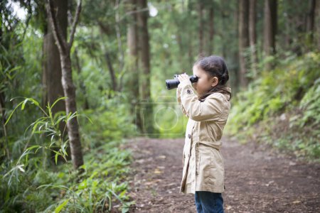 Photo for Cute girl exploring the forest with binoculars - Royalty Free Image