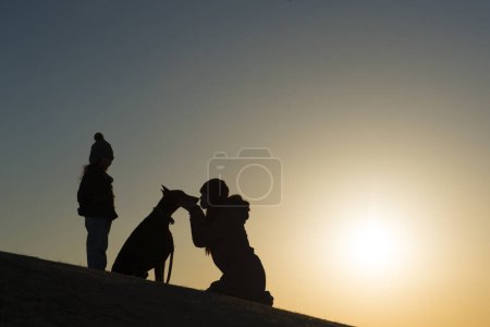 Téléchargez les photos : Silhouette de Doberman et propriétaire au coucher du soleil - en image libre de droit