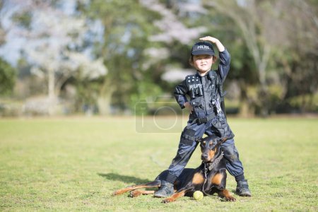 Photo for Beautiful Doberman and Little Girl in Police Costume - Royalty Free Image