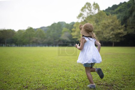 Téléchargez les photos : Petite fille courant sur le terrain dans un parc - en image libre de droit
