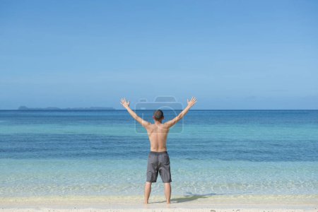 Téléchargez les photos : Homme levant les mains à la plage - en image libre de droit