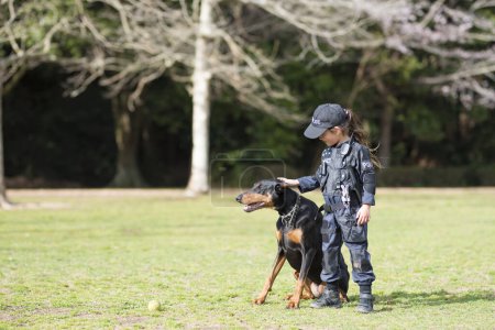 Photo for Beautiful Doberman and Little Girl in Police Costume - Royalty Free Image