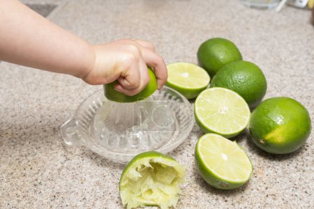 The hand of the child squeeze the lime juice
