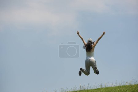 Photo for Woman to jump on hill lawn - Royalty Free Image