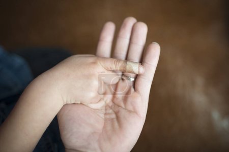 Hände von Mutter Band, das die Fingerkuppe des Kindes unterstützt