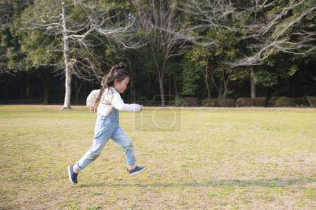 Téléchargez les photos : Mignonne petite fille asiatique n courir dans le parc - en image libre de droit