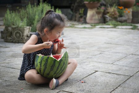 Téléchargez les photos : Asiatique enfant fille manger pastèque - en image libre de droit