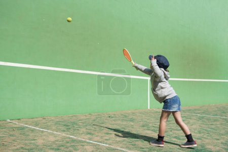 Happy little girl playing tennis