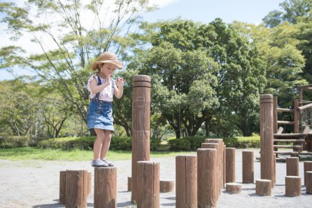 Téléchargez les photos : Mignonne petite fille asiatique jouer sur aire de jeux dans le parc - en image libre de droit